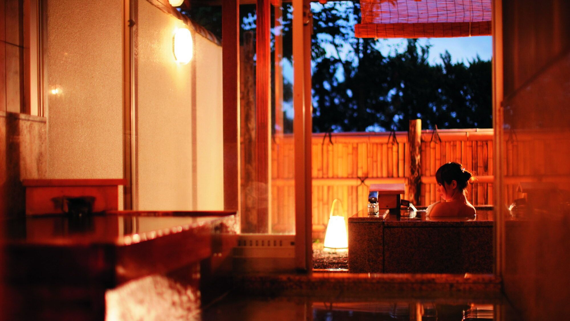 Un onsen japonais traditionnel, avec un intérieur en bois et une vue sur le ciel nocturne.