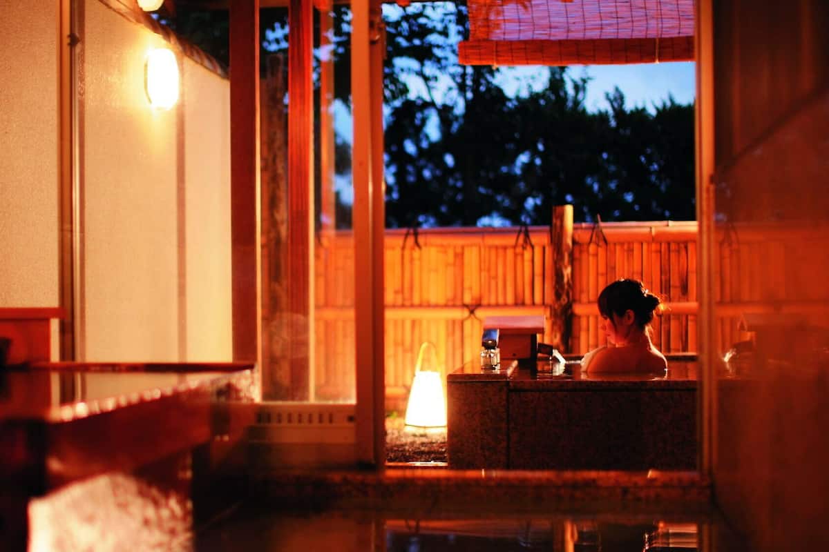 Ein traditionelles japanisches Onsen mit Holzinnenausstattung und Blick auf den Nachthimmel.