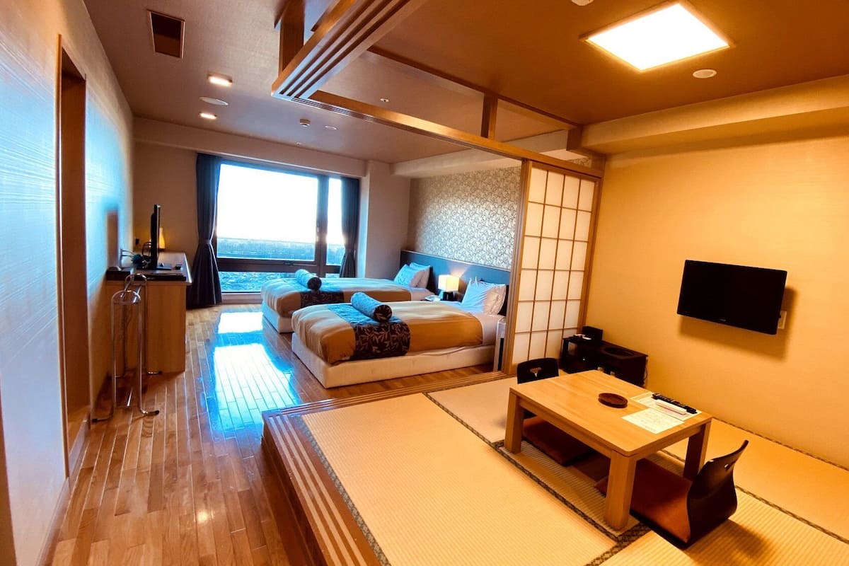 Ein Hotelzimmer mit Bett, Nachttisch, Fernseher und Meerblick.
