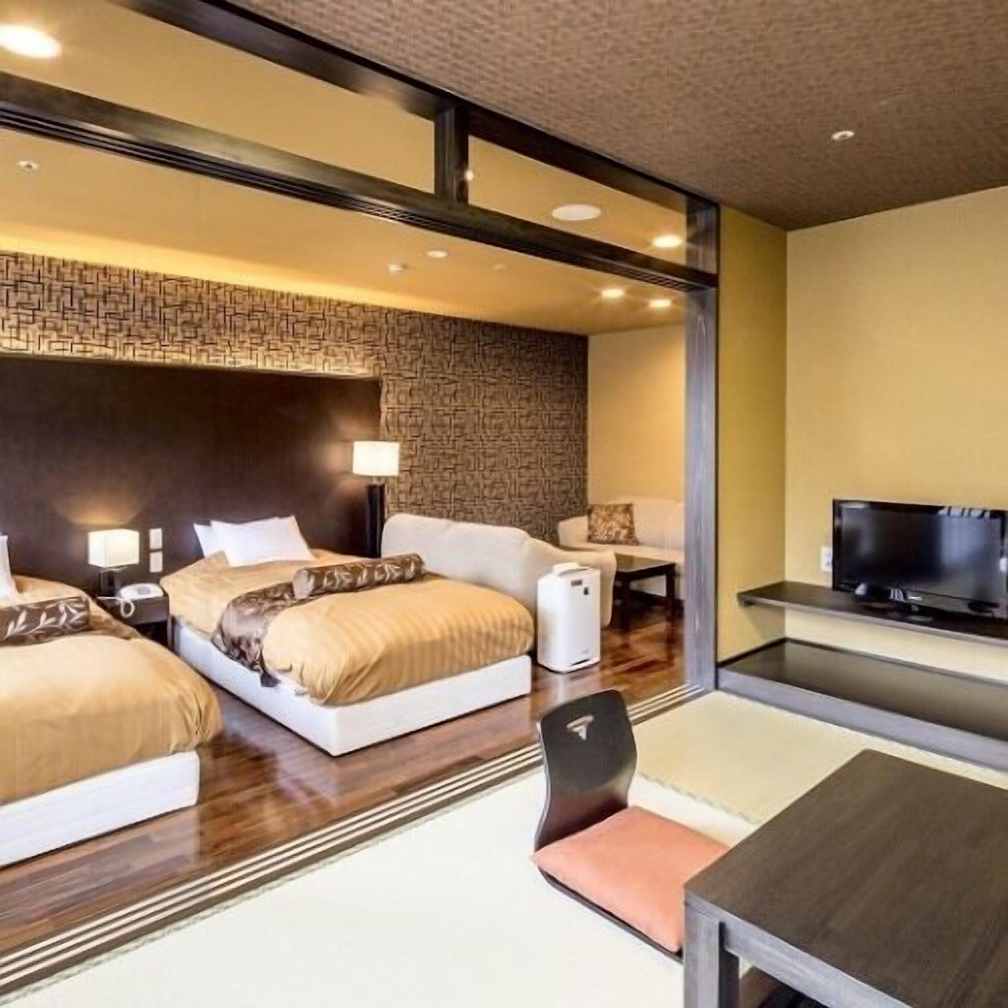 Une chambre d’hôtel avec un grand lit, un bureau, une chaise, une télévision et un radiateur fixé au mur.