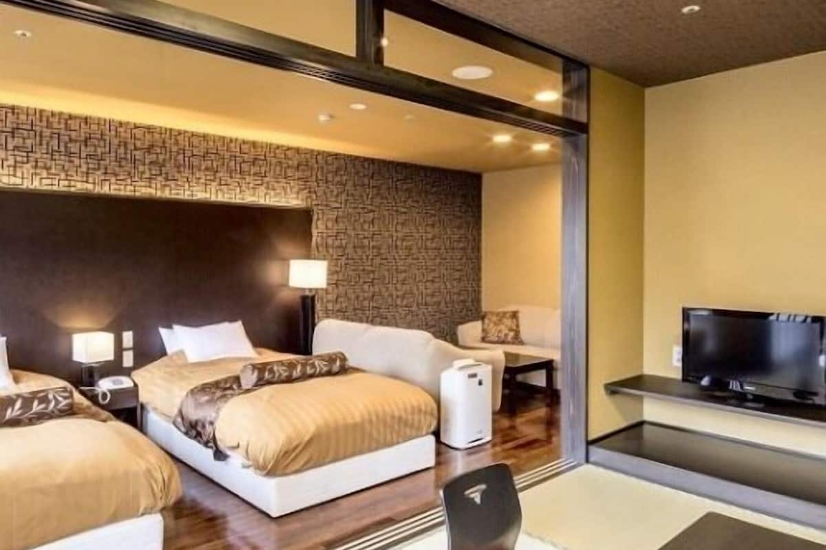 Ein Hotelzimmer mit einem großen Bett, einem Schreibtisch, einem Sessel, einem Fernseher und einer Wandheizung.