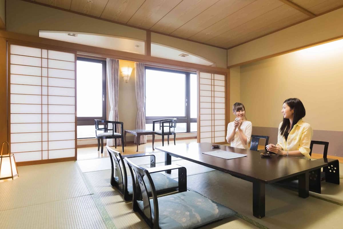 Ein traditioneller japanischer Besprechungsraum mit Tatami-Matten, einem niedrigen Tisch, Stühlen und Schiebetüren.