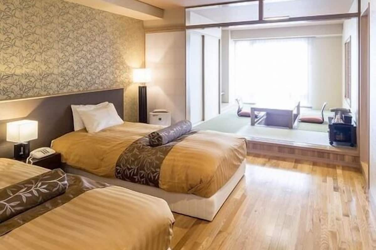 Ein Hotelzimmer mit zwei Betten, einem großen Fenster und Blick nach draußen.