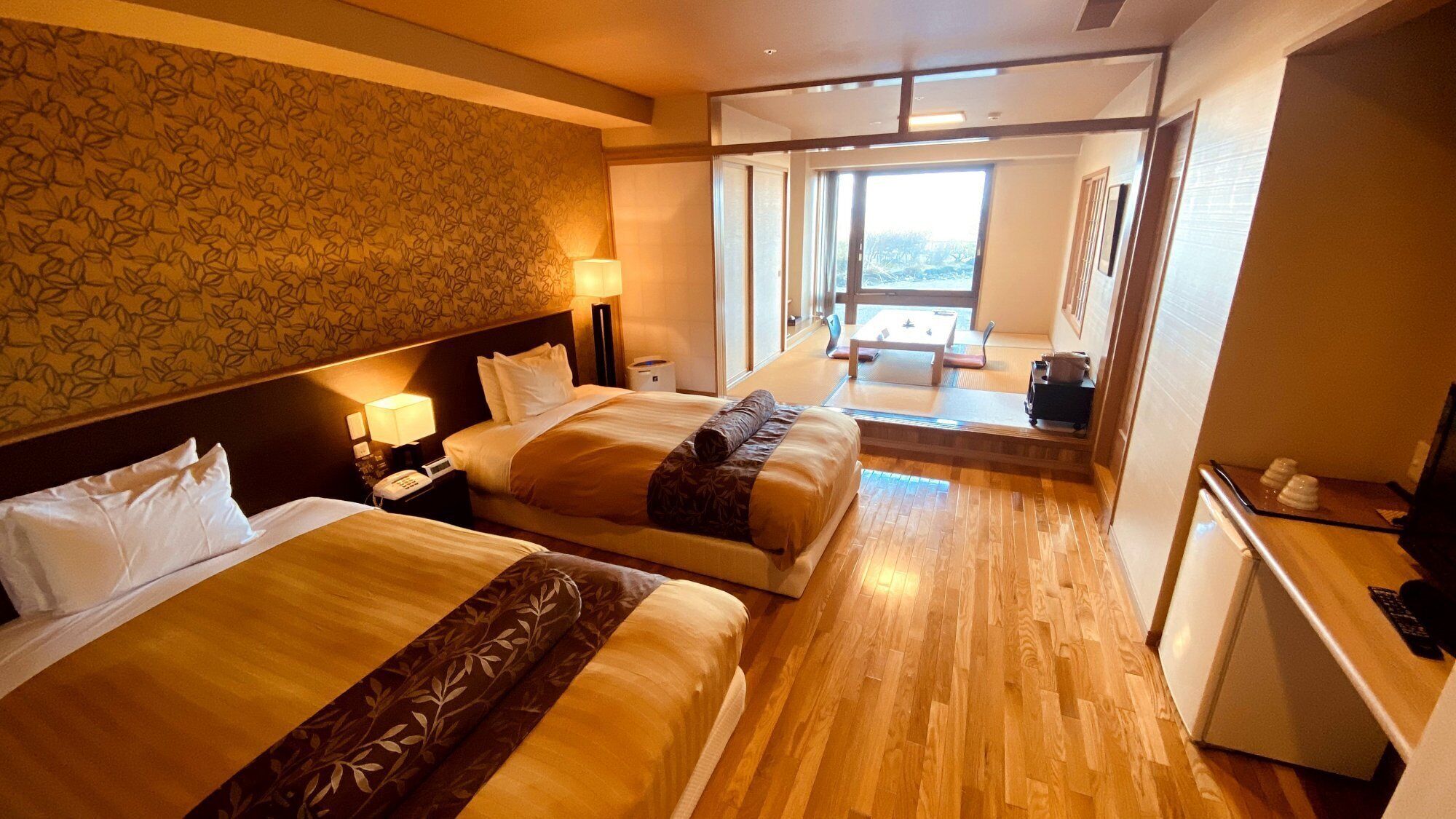 Une chambre d’hôtel avec deux lits, un bureau, une chaise et une vue sur l’extérieur.