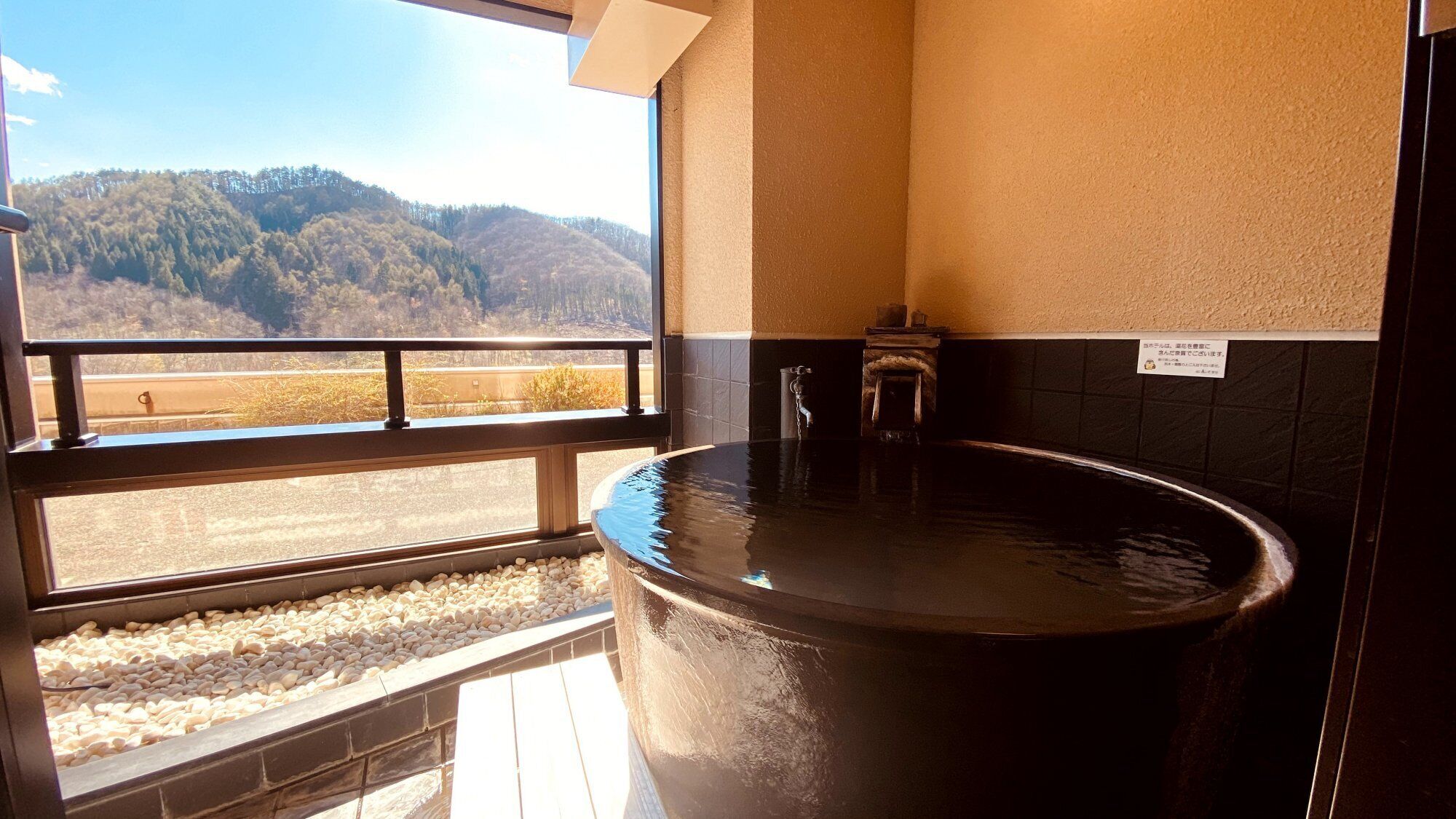 Un bain à remous avec vue sur les montagnes, une fenêtre offrant un beau panorama et un panneau accroché au mur.