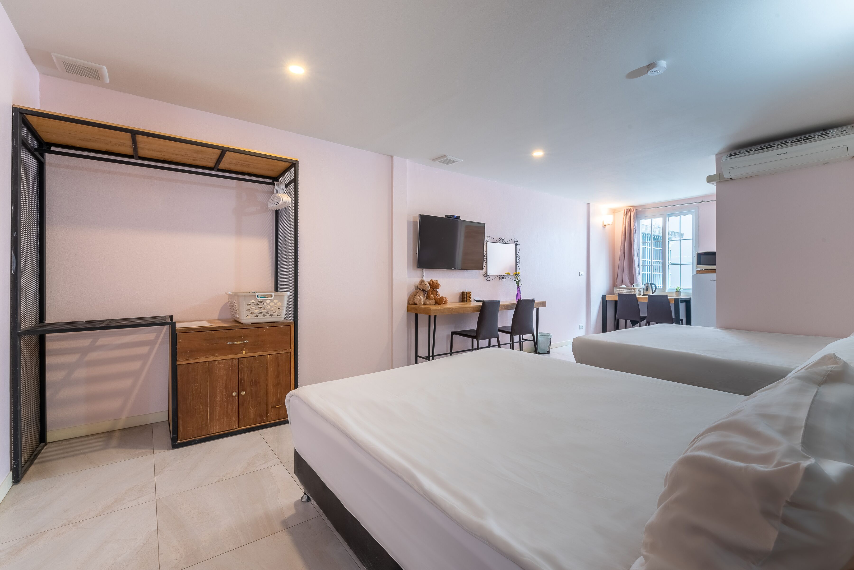 A bedroom with two beds, a desk with a chair, a TV, and a wardrobe.