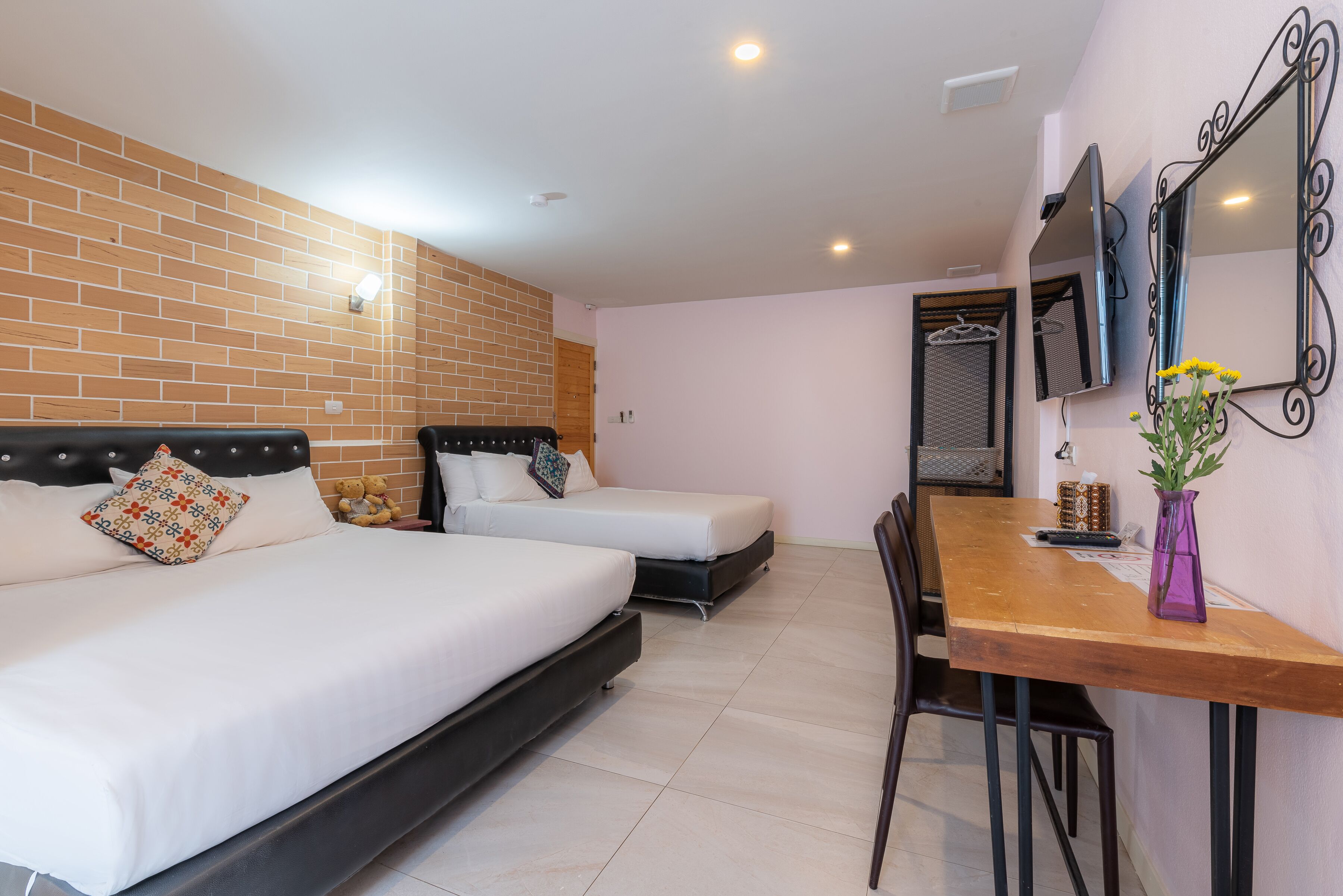 Habitación de hotel con dos camas, una mesa de comedor, televisión y espejo.
