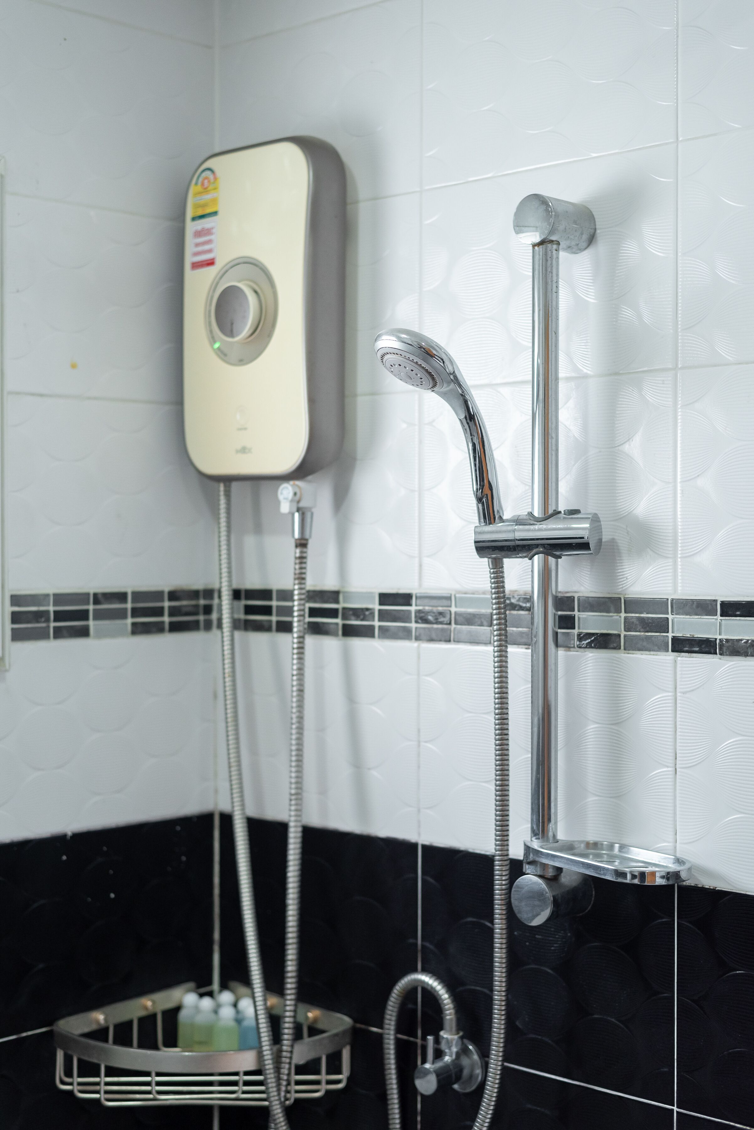 Un baño con ducha, cabezal de ducha manual y grifo de cromo.