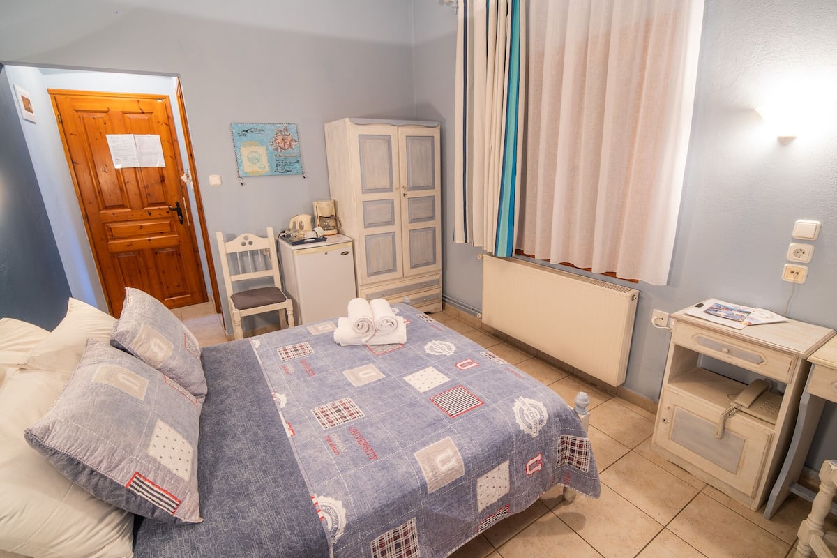 Een slaapkamer met een bed, een kledingkast, een klein tafeltje en een radiator.