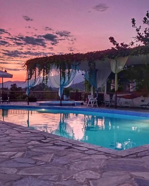 Una piscina con cubierta de piedra, rodeada por una pérgola con tela colgante.