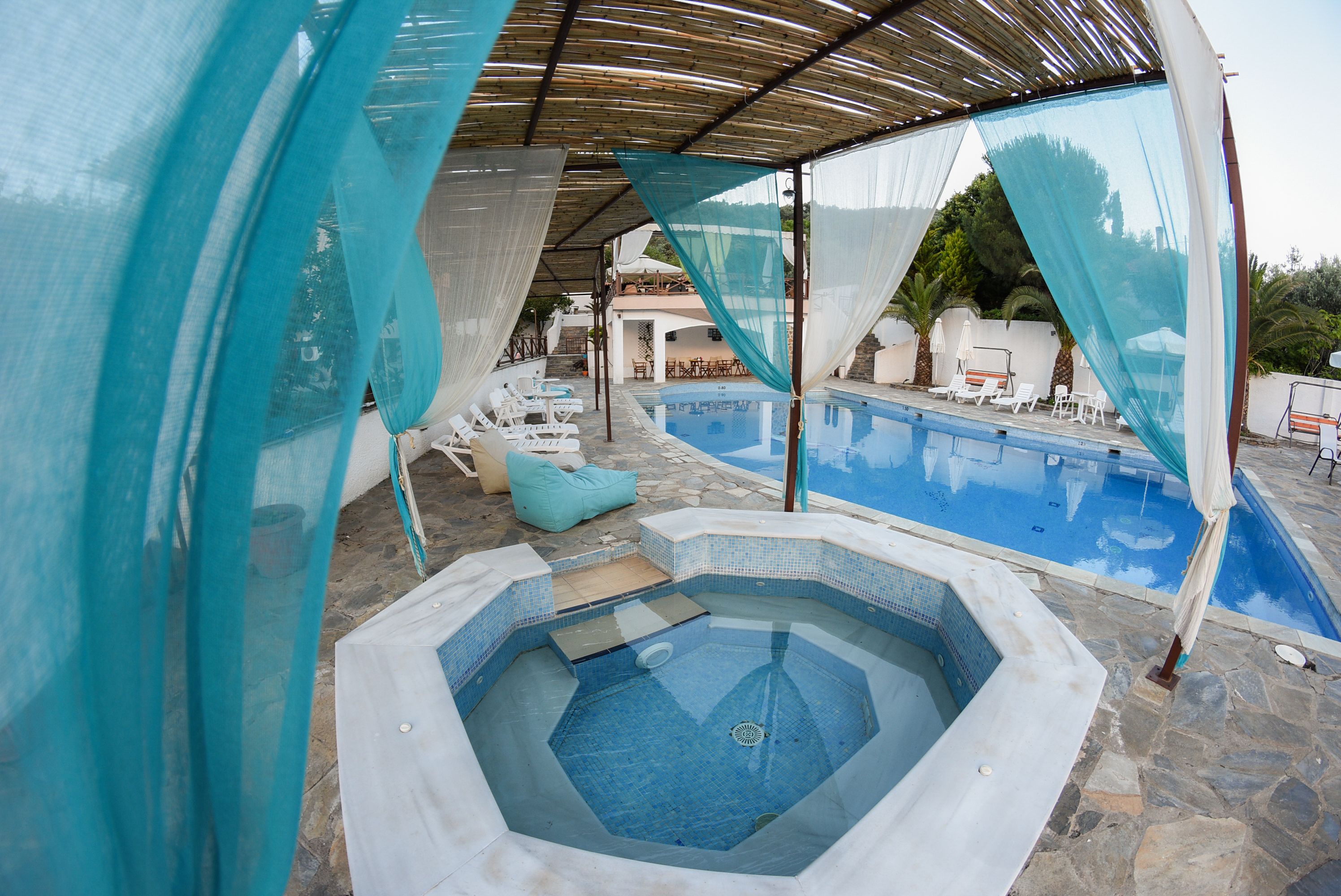 Area piscina con idromassaggio, sedie a sdraio e zona relax coperta.