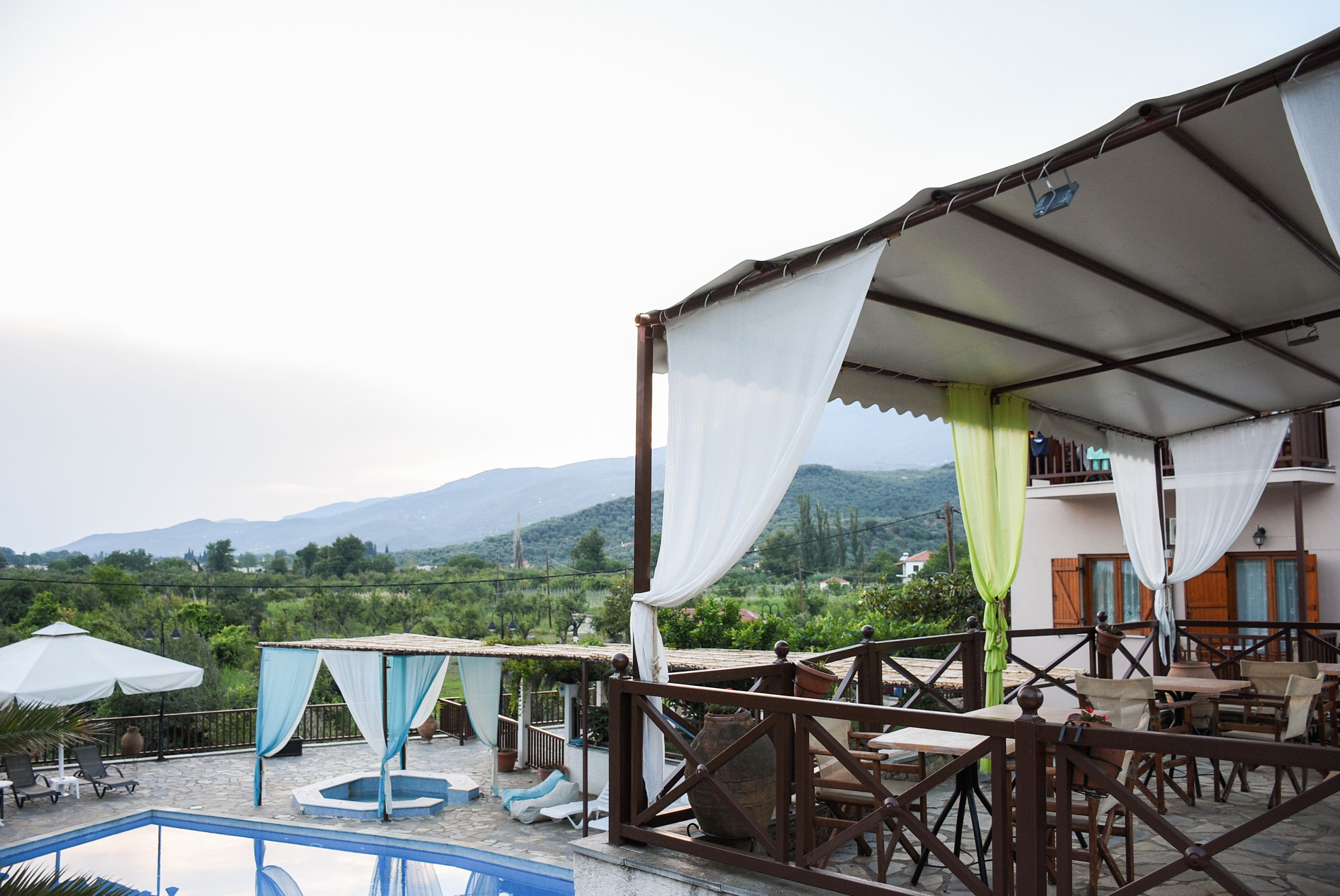 A rooftop terrace with a pool, outdoor seating, and a view of the mountains.