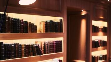 Une bibliothèque avec des étagères en bois et une seule lampe de table.