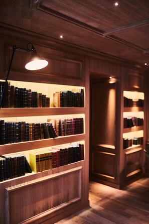 A library with wooden bookshelves and a single table lamp. - Le Clos des Terres Soudées (Vrigny)