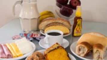 Une table de petit-déjeuner avec divers aliments, notamment des œufs, du bacon, des viennoiseries et une carafe de lait.