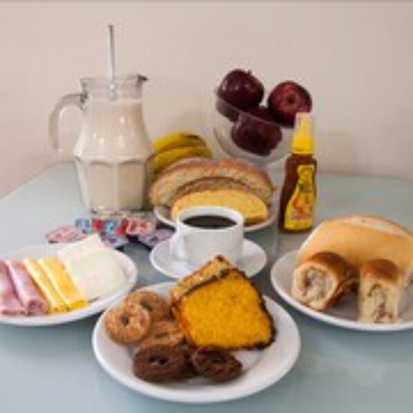 A breakfast table with various food items including eggs, bacon, pastries, and a pitcher of milk.