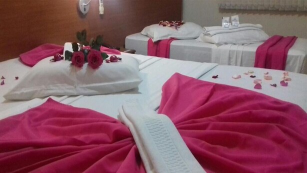 A hotel room with two beds, each with white linens and pink accents. - Hotel Rafeli (Boituva)