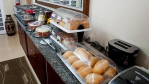 A breakfast buffet with various pastries and bread, a toaster, and a fire extinguisher on the wall. - Hotel Rafeli (Boituva)