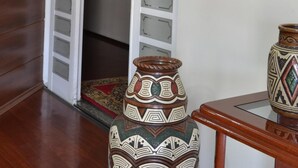 An interior with a white door leading to a room, a fire extinguisher mounted on the wall, and two decorative vases on a table. - Hotel Rafeli (Boituva)