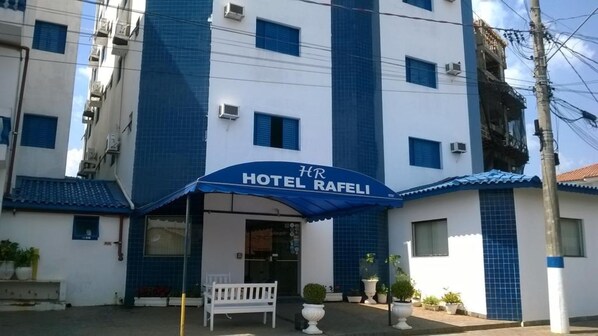 Ein Hotel namens "Hotel Rafeli" mit einer blauen Markise und einer weißen Bank davor.