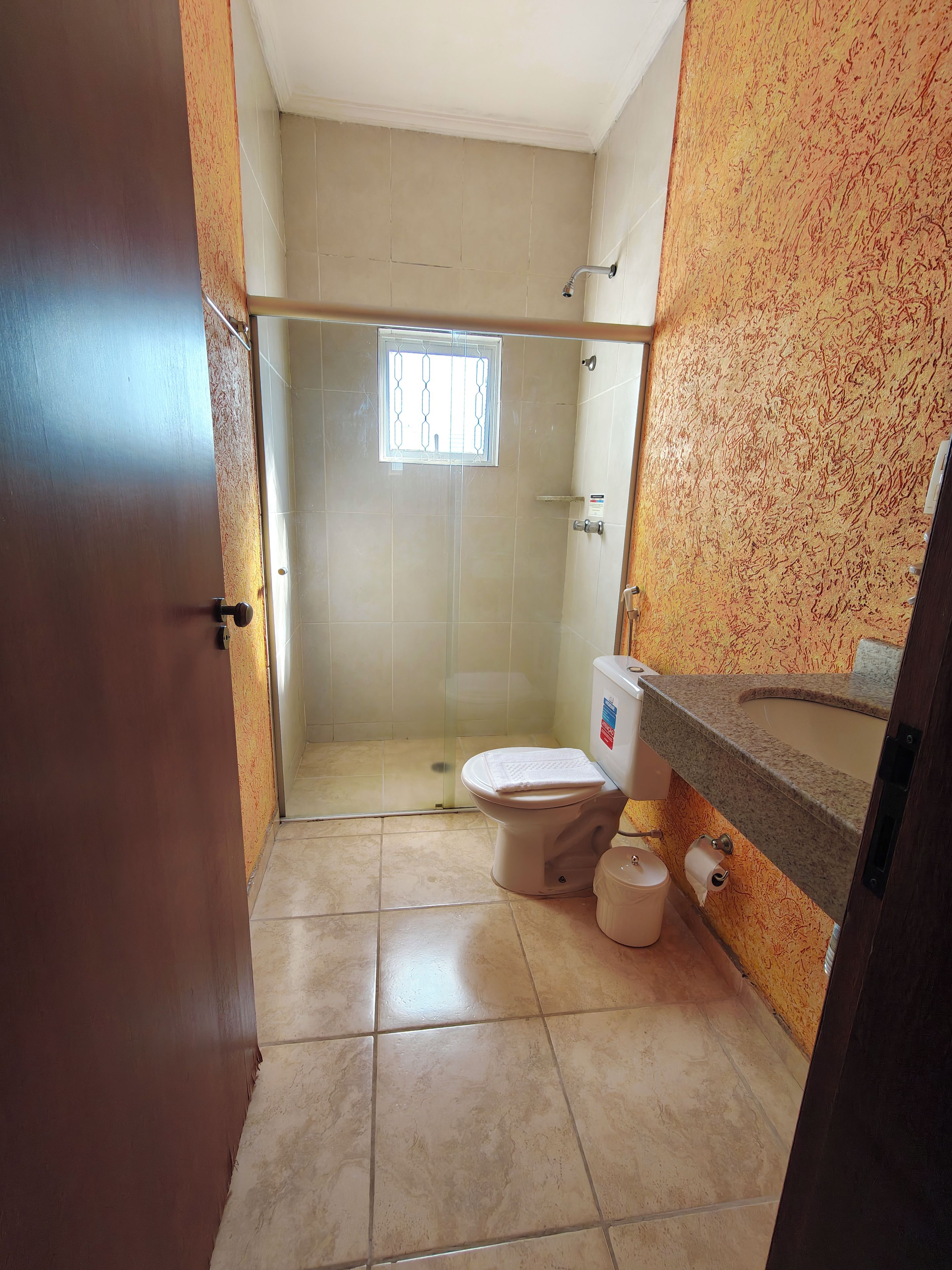 A small bathroom with a toilet, a shower, and a sink.