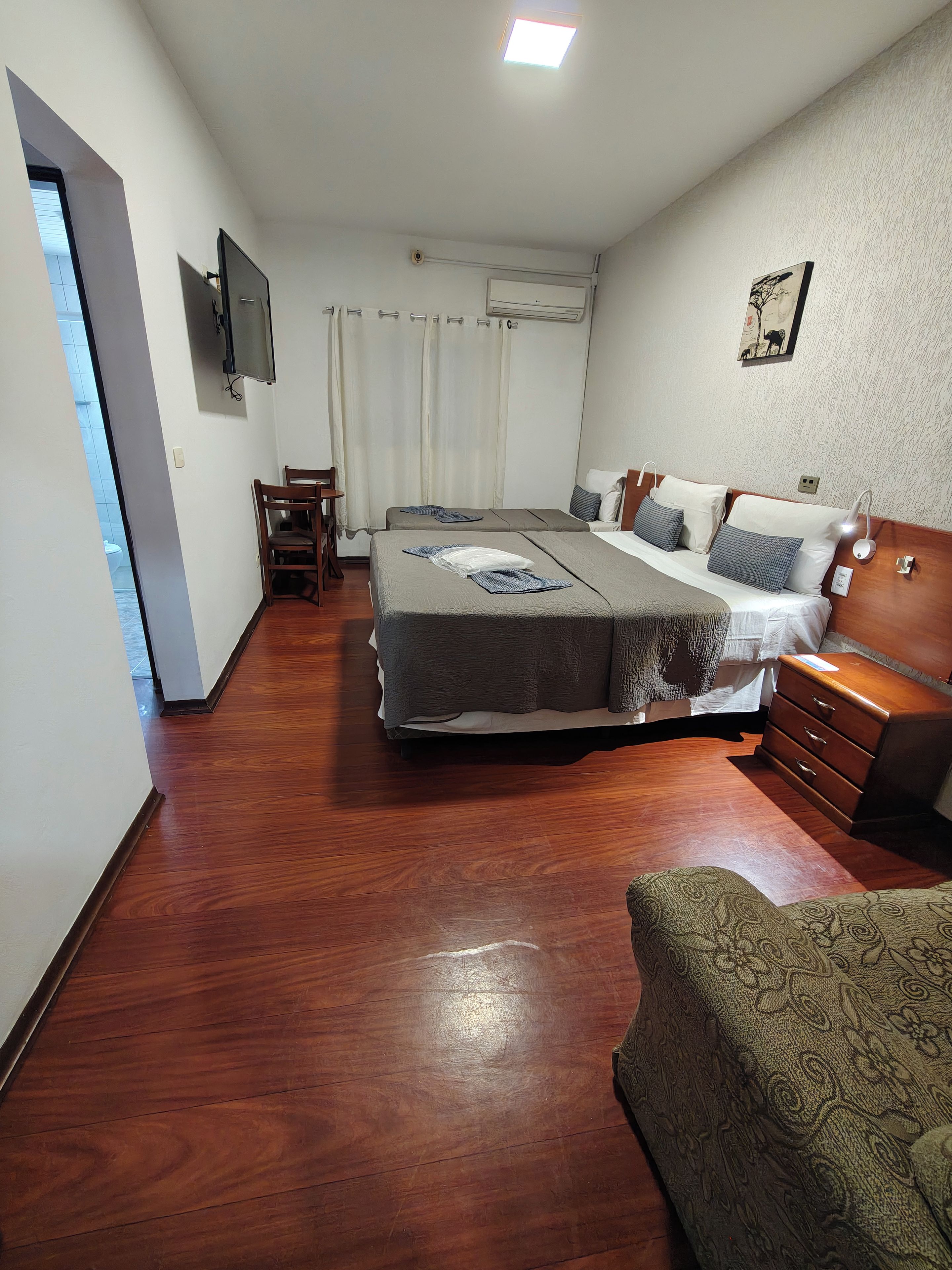 A bedroom with a bed, bedside tables, a chair, a dresser, and a television on the wall.