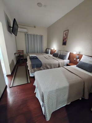 Ein Hotelzimmer mit zwei Betten, einem Schreibtisch, einem Stuhl, einem Fernseher und einem Gemälde an der Wand.