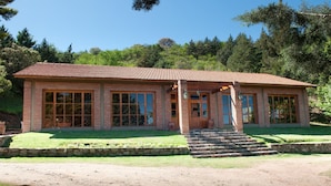 A single-story brick building with a tiled roof, large windows, and a stone staircase leading to the entrance. - Green House (Villa General Belgrano)
