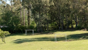 A grassy field with two soccer goals and a dense forest in the background. - Green House (Villa General Belgrano)
