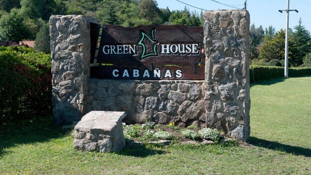 A sign for 'Green House Cabanas' with a stone structure and a grassy area in the foreground. - Green House (Villa General Belgrano)