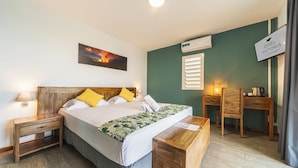 Habitación de hotel con cama, mesitas de noche, escritorio, silla, un cuadro y aire acondicionado, además de un letrero.