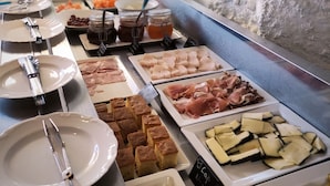 Un bufé con diferentes opciones de comida, entre ellas carnes, quesos y pan.