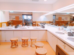 A hotel bathroom with three sinks, wicker stools, and a large mirror. - Izu Ito Hot Springs Wellness Forest Ito (Ito)