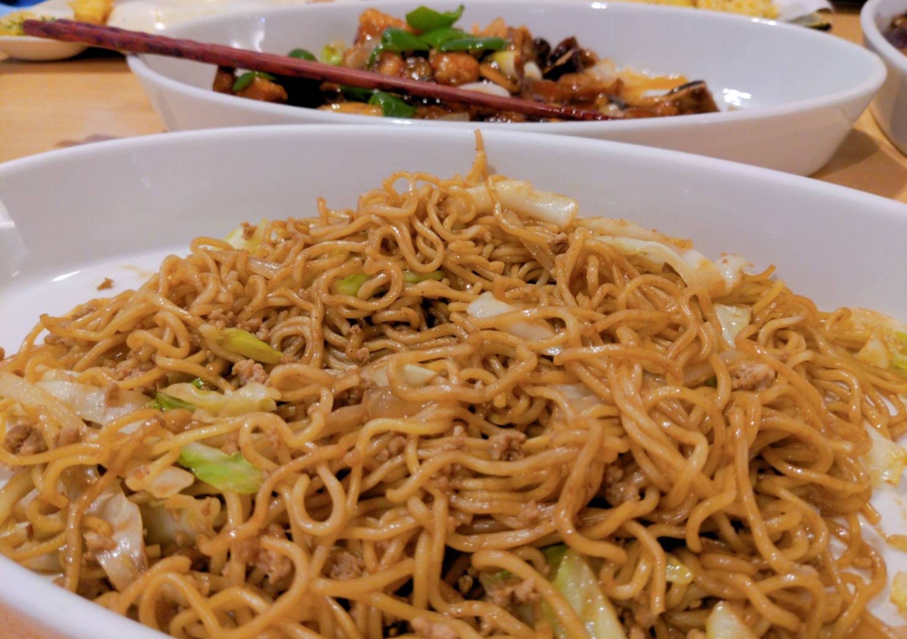 A bowl of stir-fried noodles with vegetables and meat.