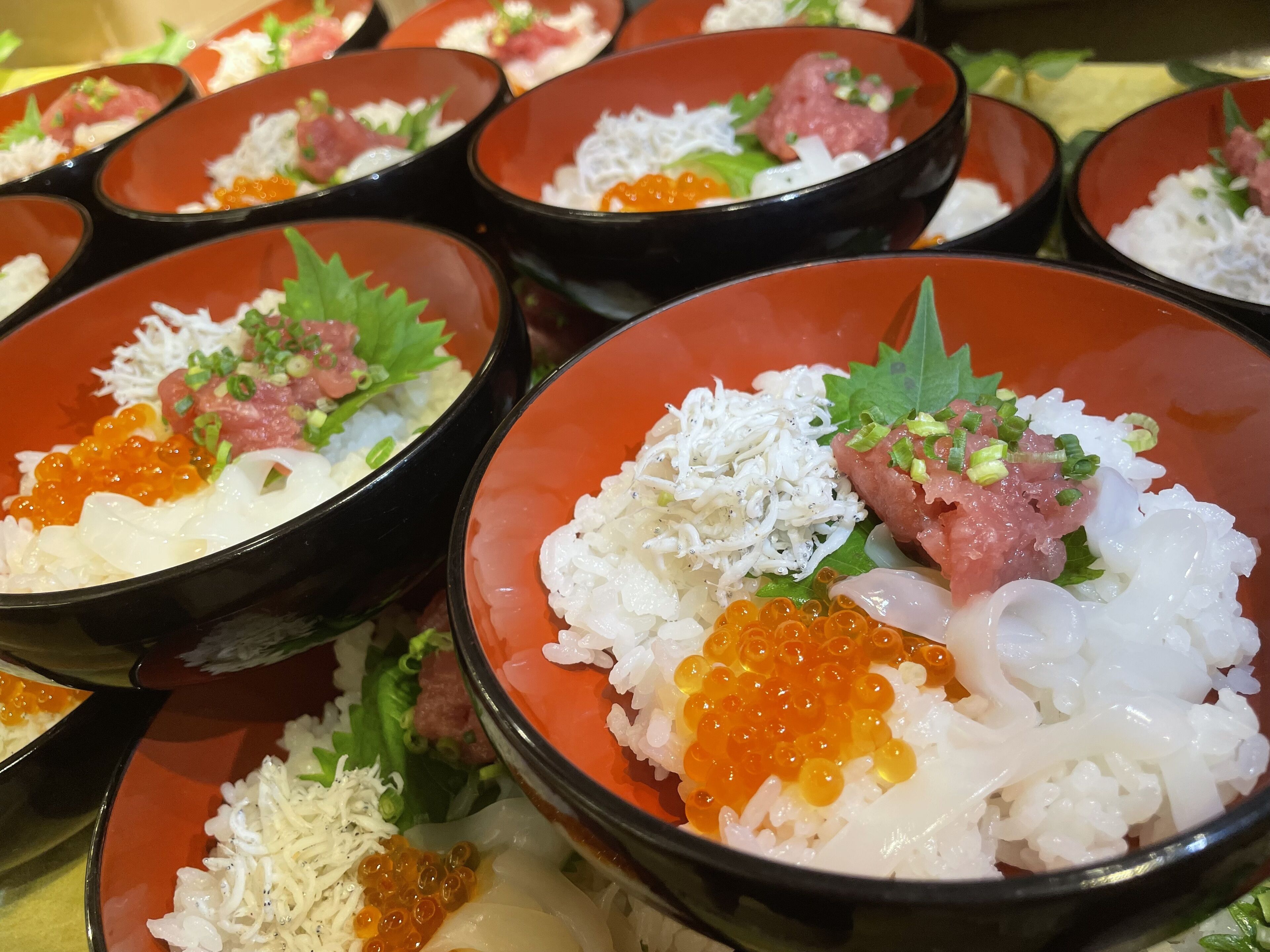 Multiple bowls of sushi with rice, fish, and garnishes.