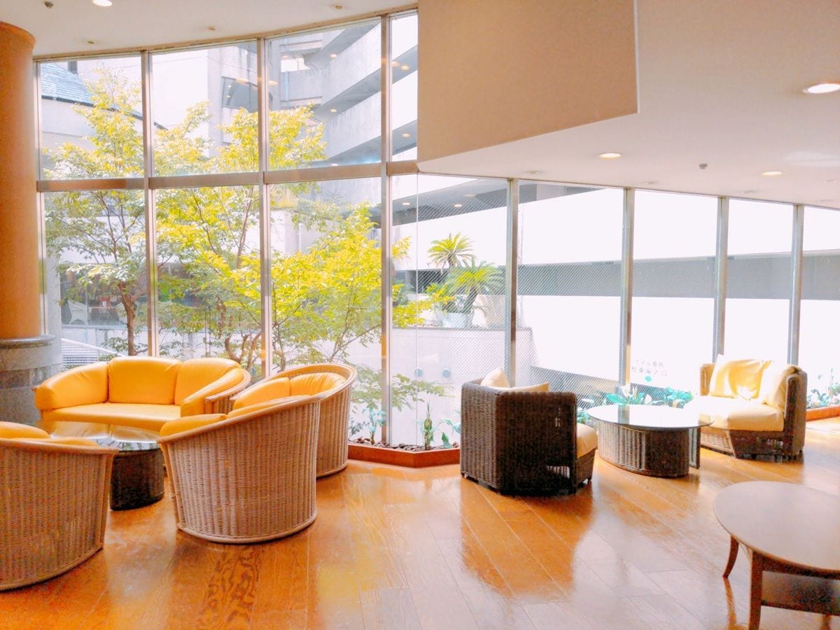 A spacious indoor area with wicker furniture, large windows, and a view of greenery outside.