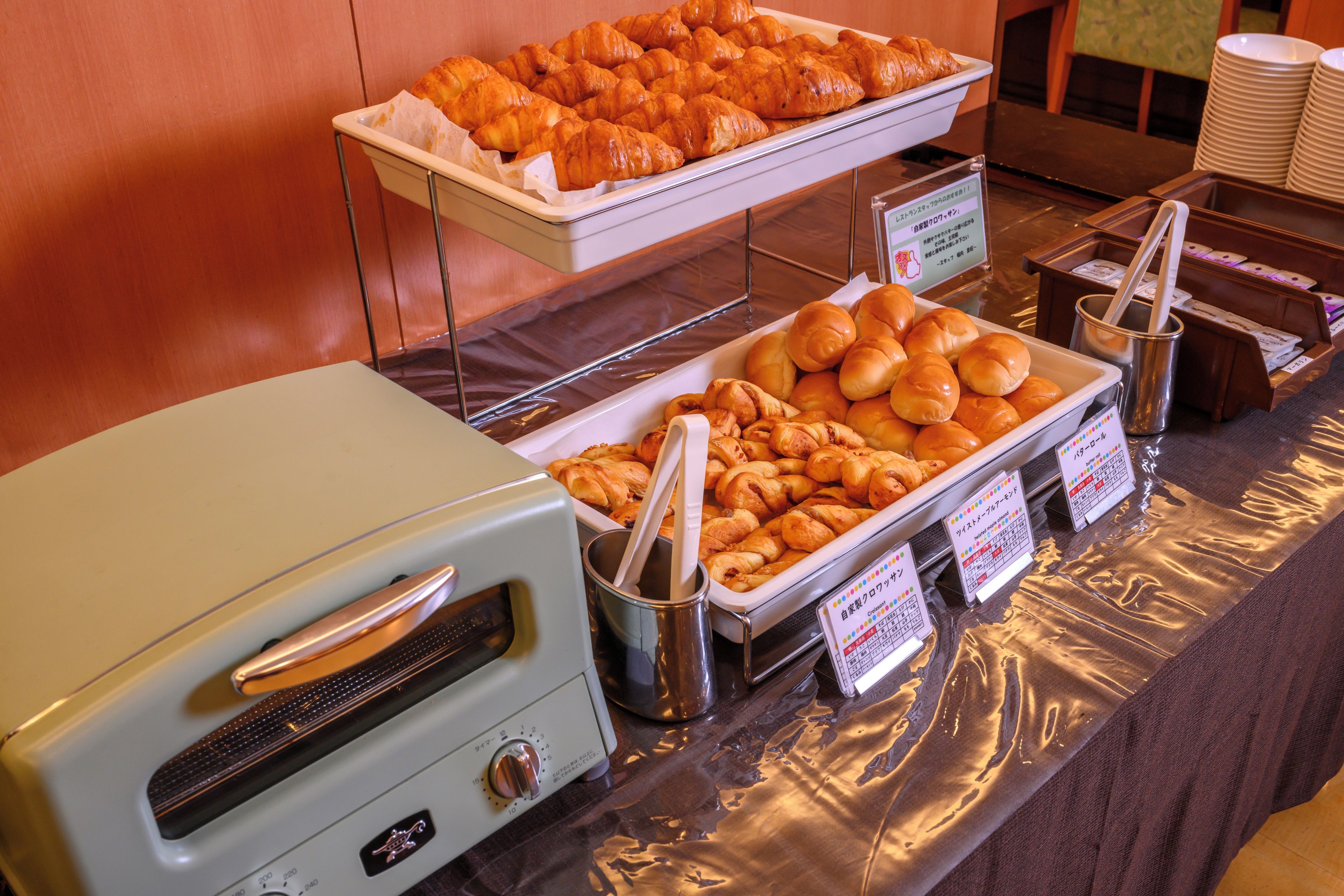 A buffet with various baked goods, including croissants and rolls, and a toaster oven.