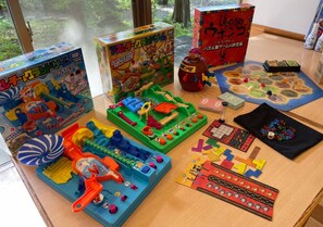 A table with various board games and toys, including a colorful toy car and a puzzle. - Wellness No Mori Ito (Ito)