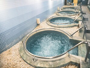 A row of hot tubs with metal railings, set against a tiled wall. - Izu Ito Hot Springs Wellness Forest Ito (Ito)