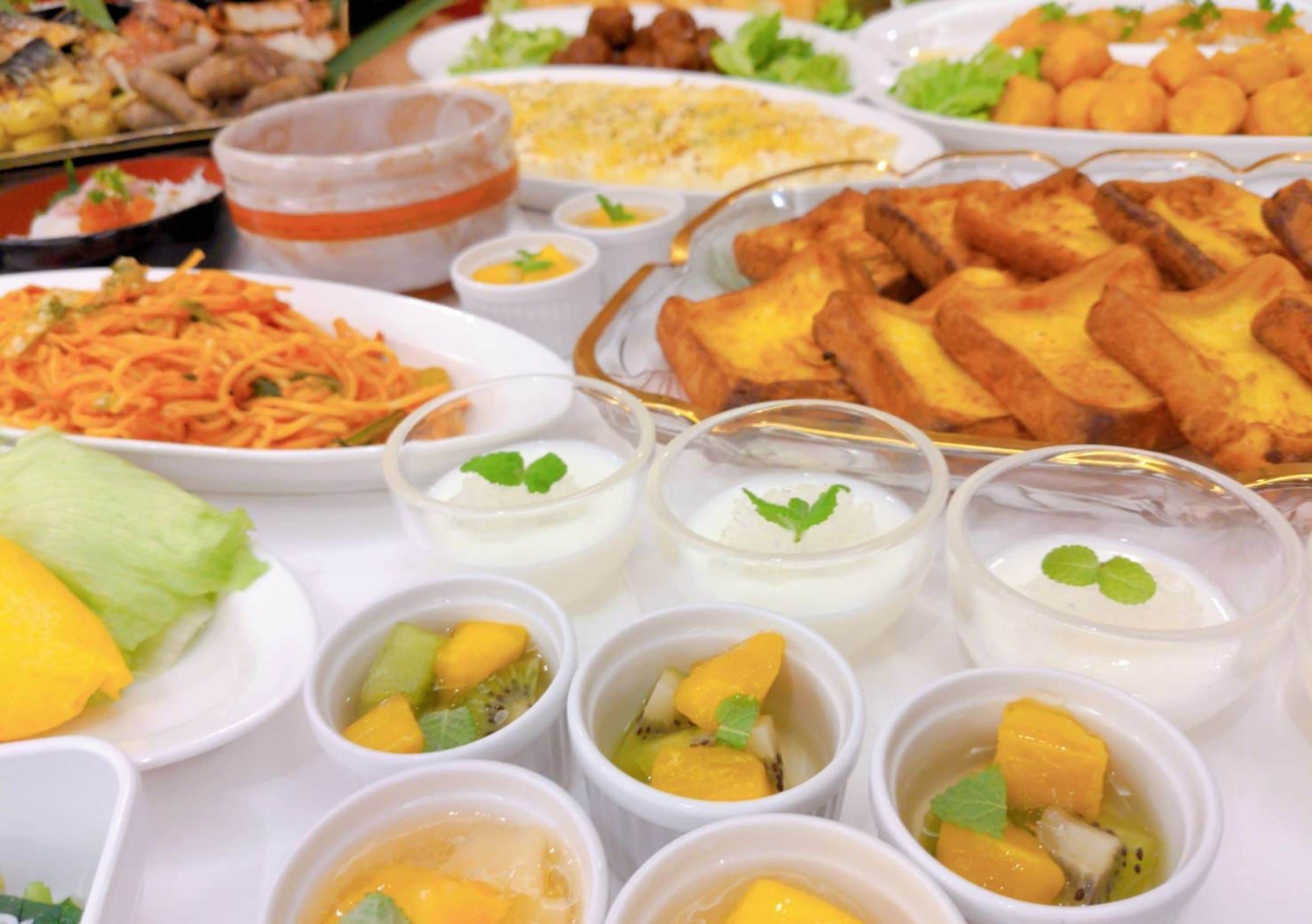 Buffet variado com diversos pratos, incluindo frituras, saladas e copos de fruta.