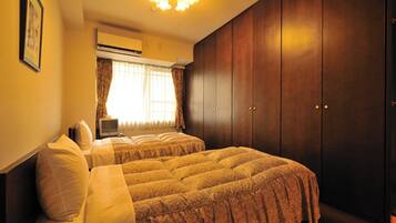 A bedroom with two beds, a wardrobe, and a television.