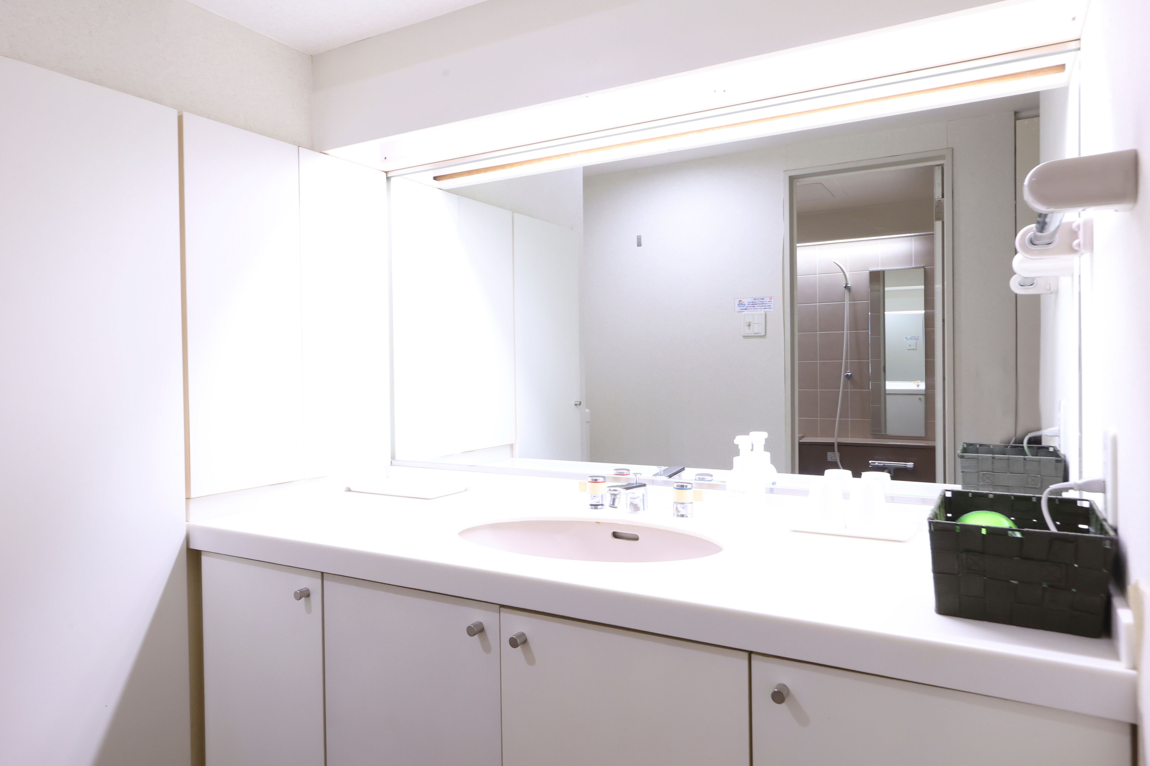 A bathroom with a white sink, mirror, and cabinets.