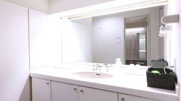 A bathroom with a white sink, mirror, and cabinets.