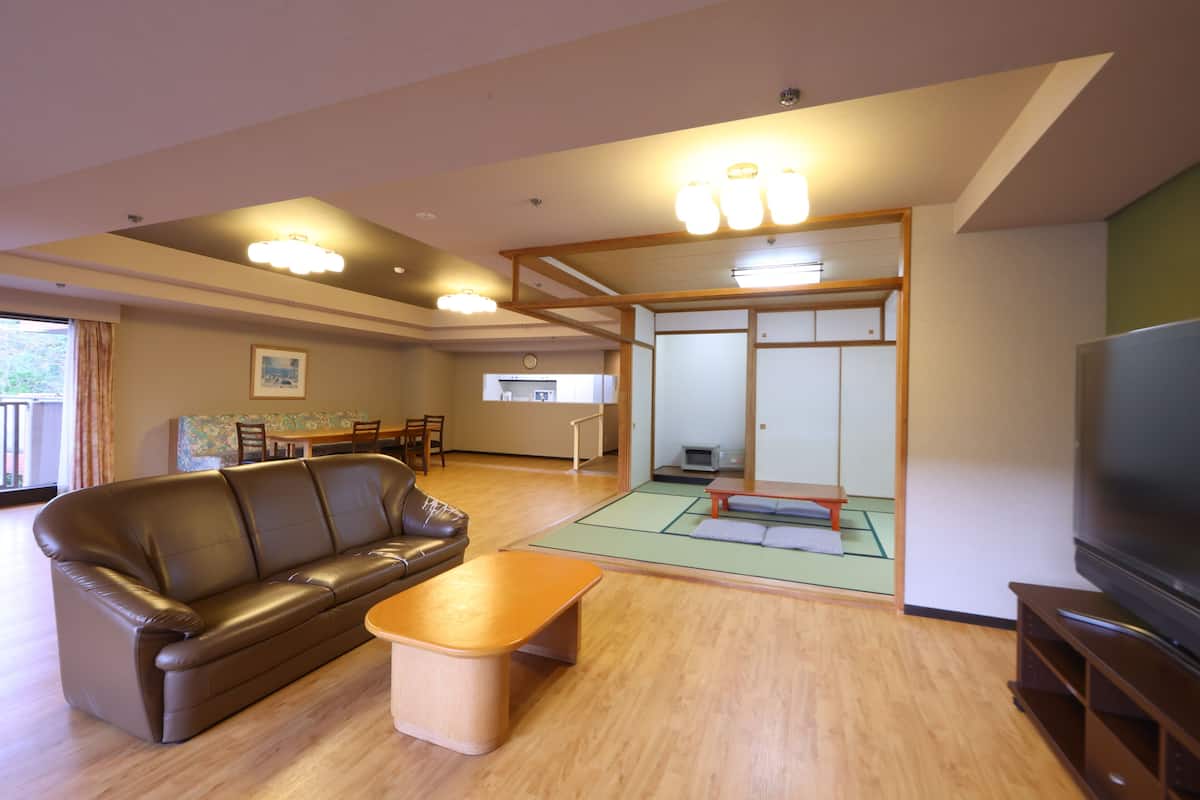 A living room with a brown leather sofa, a wooden coffee table, and a television on a wooden stand.