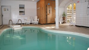 Ein Schwimmbad mit einer Holzsauna, weiß geflieste Wände und einer Tür mit der Aufschrift 'BAUHAUS'.