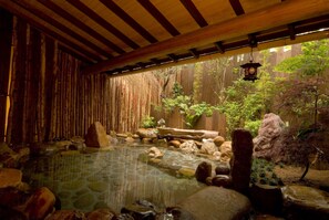 A traditional Japanese onsen with a stone hot spring, wooden beams, and a bamboo fence. - Hotel & Spa Resort LA VISTA Izusan (Atami)