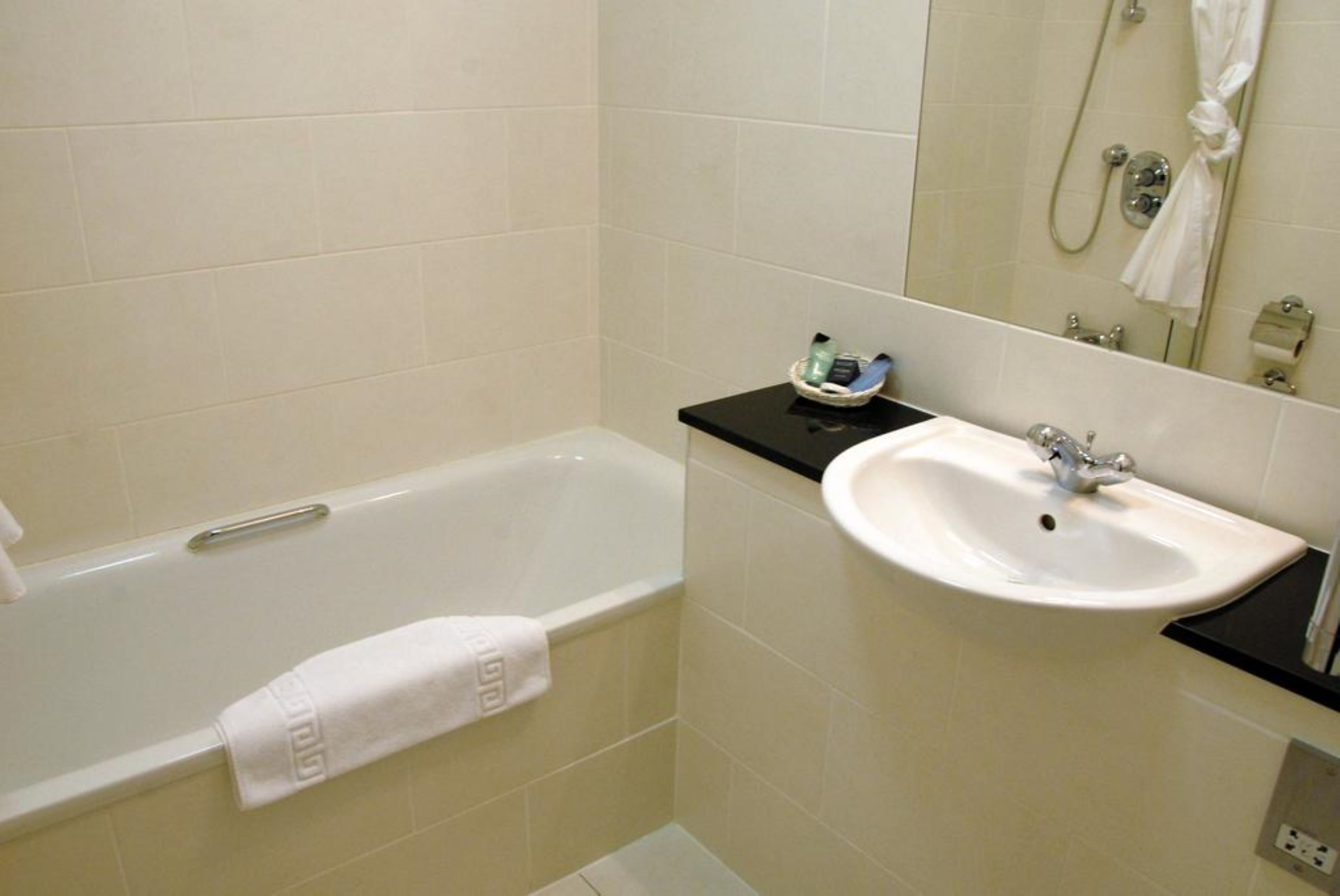 A bathroom with a bathtub, a sink, and a mirror.
