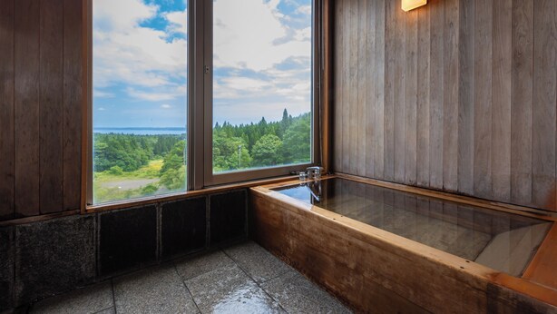 Un interior de madera con un ventanal grande, una bañera y una pared de madera.