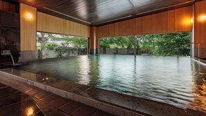 Piscina interior moderna con paredes y techo de madera, ventanas amplias y un borde de piedra.