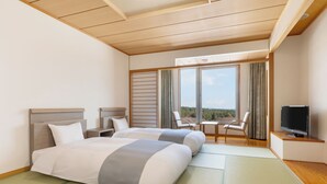 Habitación de hotel con dos camas, televisión, una silla y vista al exterior.